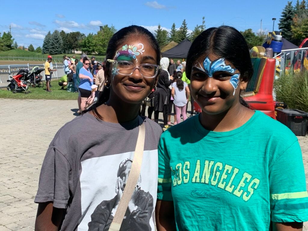 Two young girls pose with painted faces at Family Fun Day 2023